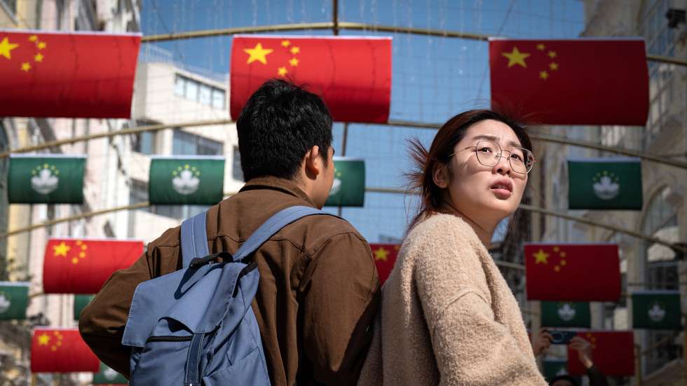 epa11785051 People walk past Chinese flags during the visit of the Chinese President to celebrate the 25th anniversary of the establishment of the Macau Special Administrative Region (MSAR) in Macau, China, 19 December 2024.  EPA/GONCALO LOBO PINHEIRO