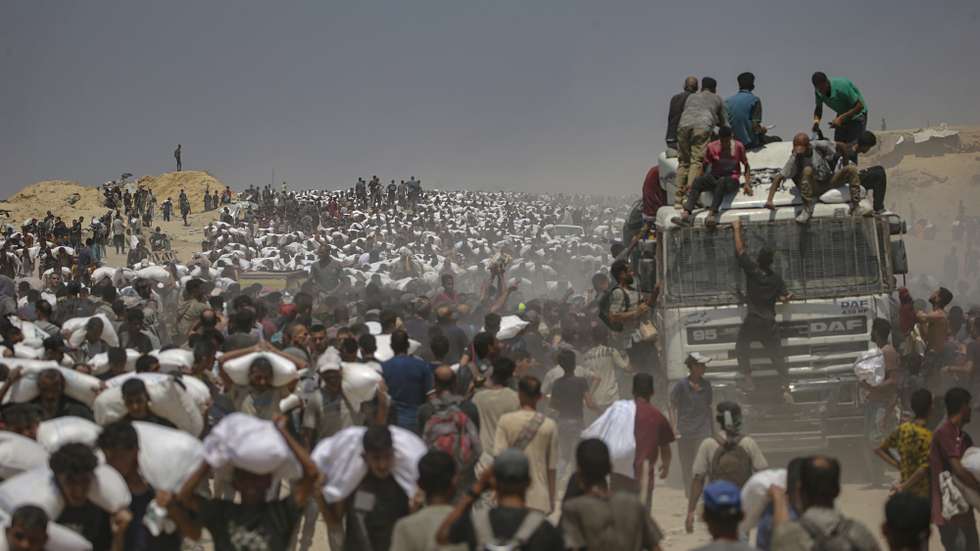 epaselect epa12266100 Internally displaced Palestinians carry bags of flour near a food distribution point in Zikim, northern Gaza Strip, 27 July 2025. The Israeli army declared a 'tactical pause' in military operations in parts of the Gaza Strip on 27 July, to facilitate the safe passage of humanitarian aid convoys. More than 130 Palestinians, the majority of whom children, have died of malnutrition in the Gaza Strip, the Palestinian Ministry of Health said on 27 July.  EPA/MOHAMMED SABER