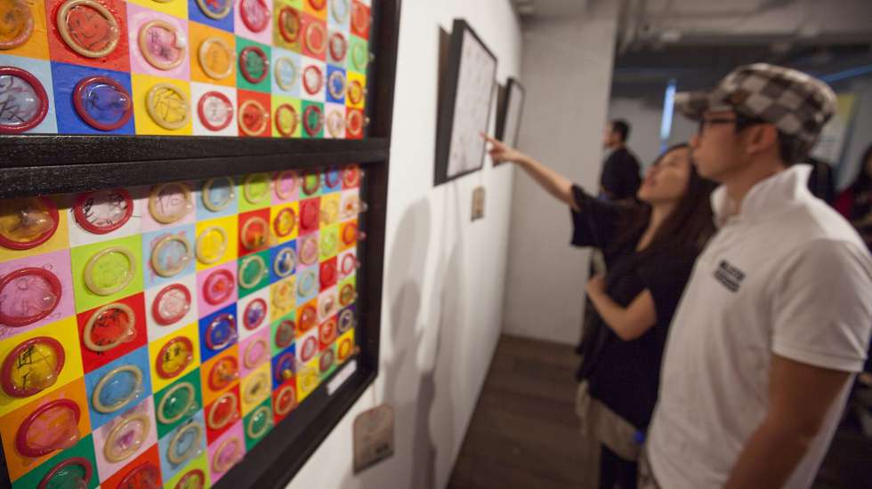 epa03925097 Visitors to the Hong Kong Sex Cultural Festival 2013 admire a piece of art made out of condoms and made by sex workers, Hong Kong, China, 26 October 2013. The three day event, which kicks of today, aims to raise awareness on lesbian, gay, bisexual and transgender (LGBT) issues, as well as the plight of sex workers in Hong Kong, and is sponsored by the Hong Kong Sex Eduction Association, the Family Planning Association of Hong Kong, and the Hong Kong Government Equal Opportunites Commission.  EPA/ALEX HOFFORD