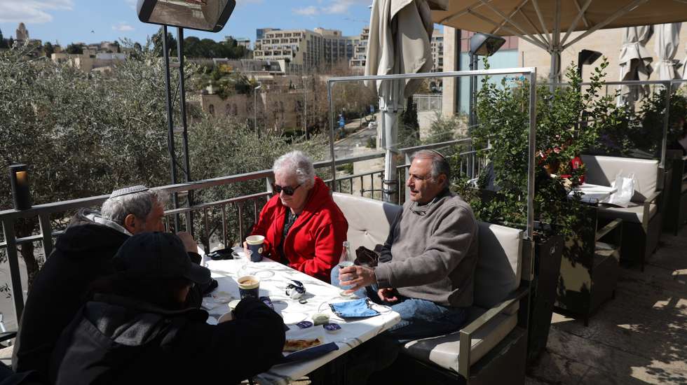 epa09027602 People sit at a coffe at the Mamila Shopping Boulevard in Jerusalem, 21 February 2021.  Israel reopened cultural hubs, and shopping malls after they were closed due to the coronavirus pandemic.  EPA/ABIR SULTAN