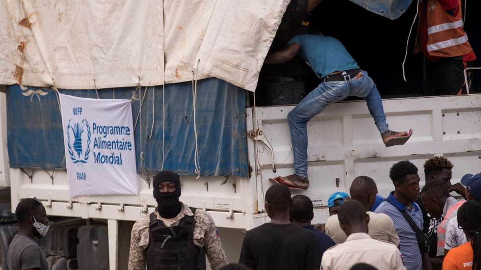 epa09422639 An employee climbs onto a World Food Program truck to deliver food to earthquake victims at Camp Perrin, Haiti, 20 August 2021. At least four trucks from the international NGO Food For The Poor were looted this 20 August on the South Highway as they prepared to deliver aid to the victims of the earthquake that caused thousands of victims and destruction in the southwest and other areas of Haiti last 14 August. 'It is with outrage that we learn that unidentified individuals have looted 4 trucks that were going to bring aid to the affected populations' the organization said in a statement published in Creole.  EPA/Orlando Barria