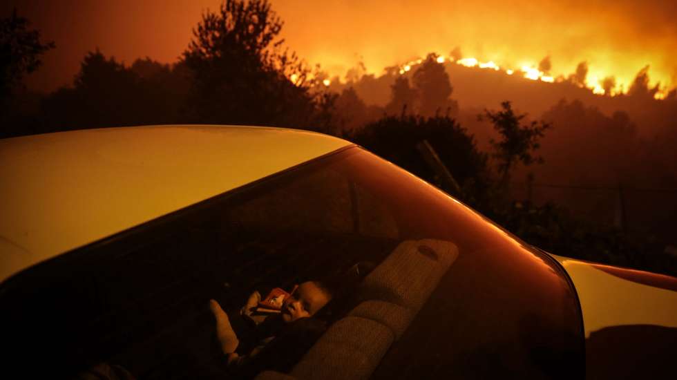 Uma criança aguarda dentro de um carro ao pé dàs chamas que consomem floresta durante um incêndio em Oliveira de Frades, 7 de setembro de 2020. Este incêndio no concelho de Oliveira de Frades, no distrito de Viseu, mobilizou 327 bombeiros, apoiados por 103 viaturas e oito meios aéreos. NUNO ANDRÉ FERREIRA/LUSA