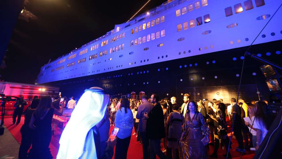 epa06730080 People stand outside the legendary Queen Elizabeth II hotel at Port Rashid, Dubai, United Arab Emirates, 10 May 2018 (issued 12 May 2018). The retired ocean liner Queen Elizabeth 2 has been operating as a floating hotel in Dubai since 18 April 2018.  EPA/ALI HAIDER