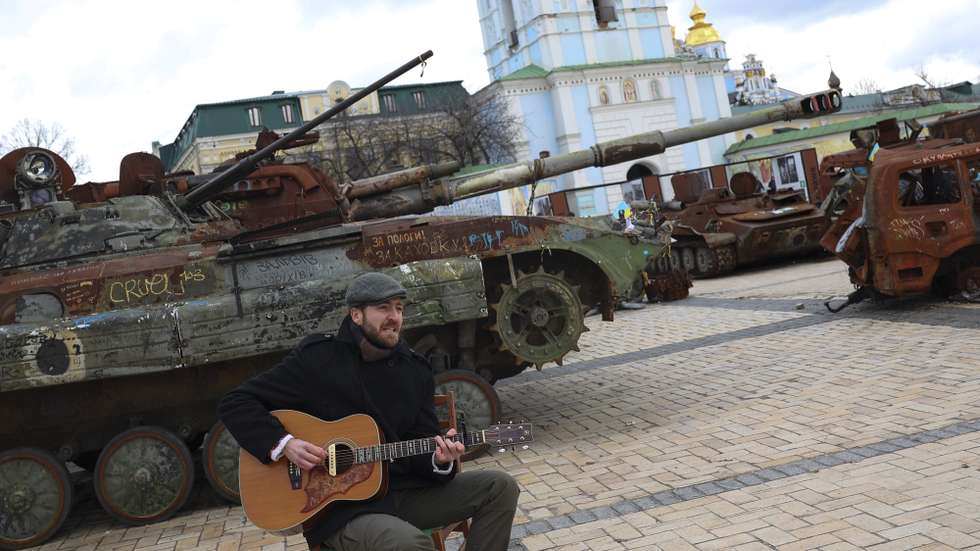 A musician plays near russian combat cars, destroyed by the ukrainian army during an exhibition at Sofievskaya Square, in Kiev, Ukraine, 04 February 2024. ANTONIO COTRIM/LUSA