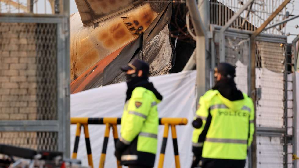 epa11796986 Police forces stand near the wreckage of the Jeju Air aircraft at Muan International Airport in Muan, 288 kilometers southwest of Seoul, South Korea, 29 December 2024. According to the National Fire Agency, a passenger jet carrying 181 people erupted in flames after going off the runway at an airport in South Korea's southwestern county of Muan on 29 December, leaving at least 62 people dead.  EPA/HAN MYUNG-GU