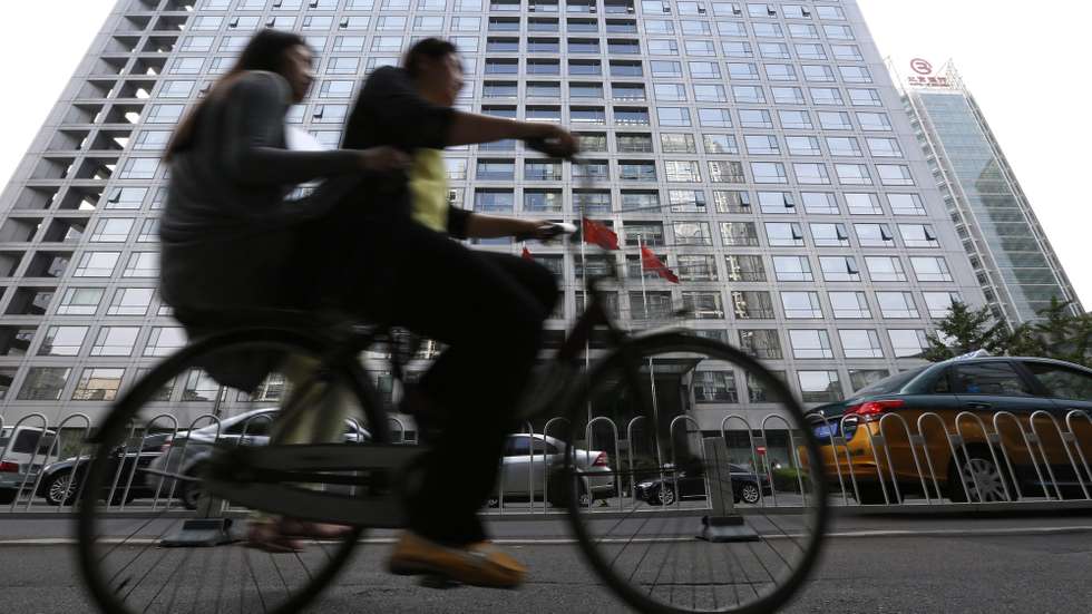epa04838179 Chinese cyclists cycle past the China Securities Regulatory Commission building in Beijing, China, 09 July 2015. The country's securities regulator said on 08 July that big shareholders who hold more than five per cent of a company's shares must not reduce their holdings in the coming six months.  EPA/HOW HWEE YOUNG