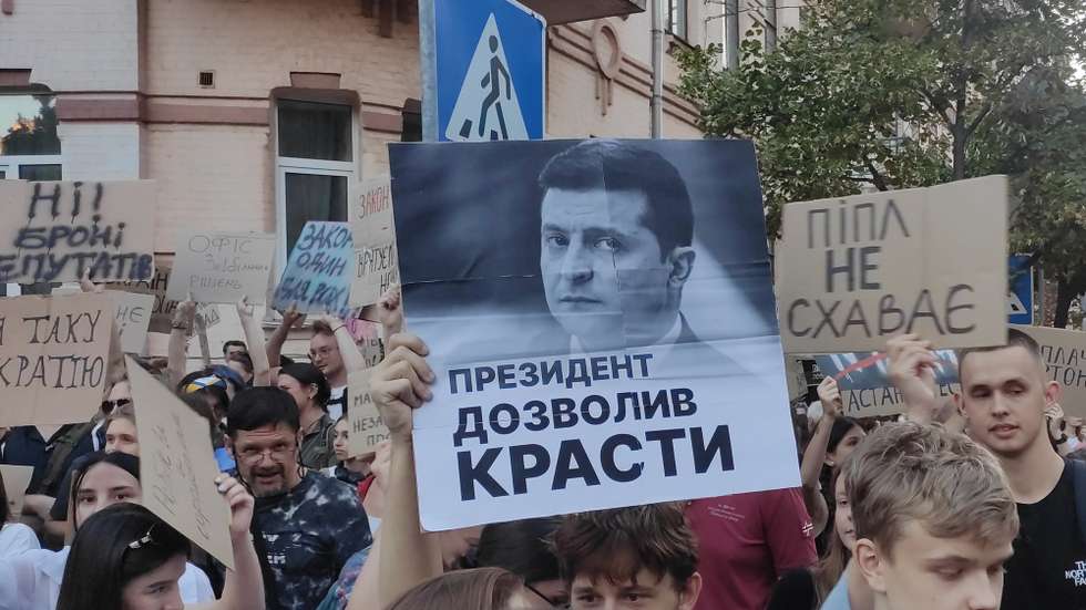 epa12257262 Protesters hold signs during a demonstration in Kiev, Ukraine, 23 July 2025. Thousands of Ukrainians gathered on the second day of protests against the passage of a law that critics believe strips two key anti-corruption agencies of their independence by placing them under state control.  EPA/Rostyslav Averchuk