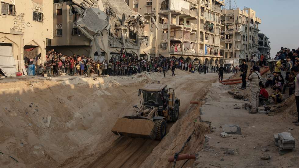 epaselect epa12460750 Locals gather to watch as an excavator works at the site where members of the Al-Qassam Brigades, the military wing of the Hamas movement, are searching for the bodies of Israeli hostages in an area in Hamad City, Khan Younis, in the southern Gaza Strip, 17 October 2025.  EPA/HAITHAM IMAD