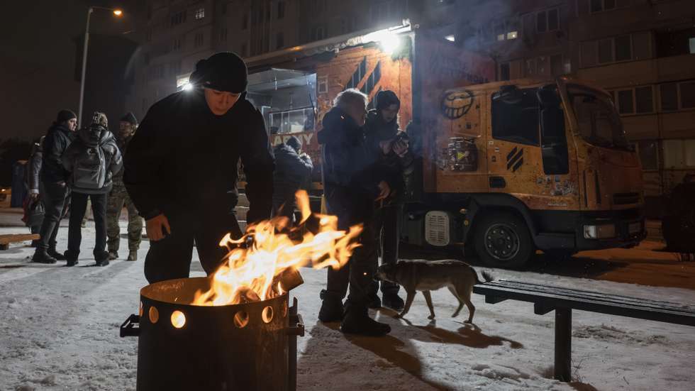 epa12688383 Residents gather around a fire at a mobile kitchen in Kyiv, Ukraine, 28 January 2026, amid the Russian invasion. Organized by veterans of the 3rd Separate Assault Brigade, the station provides food and warmth to those left without power or heat following Russian strikes on the city's critical infrastructure.  EPA/MAXYM MARUSENKO