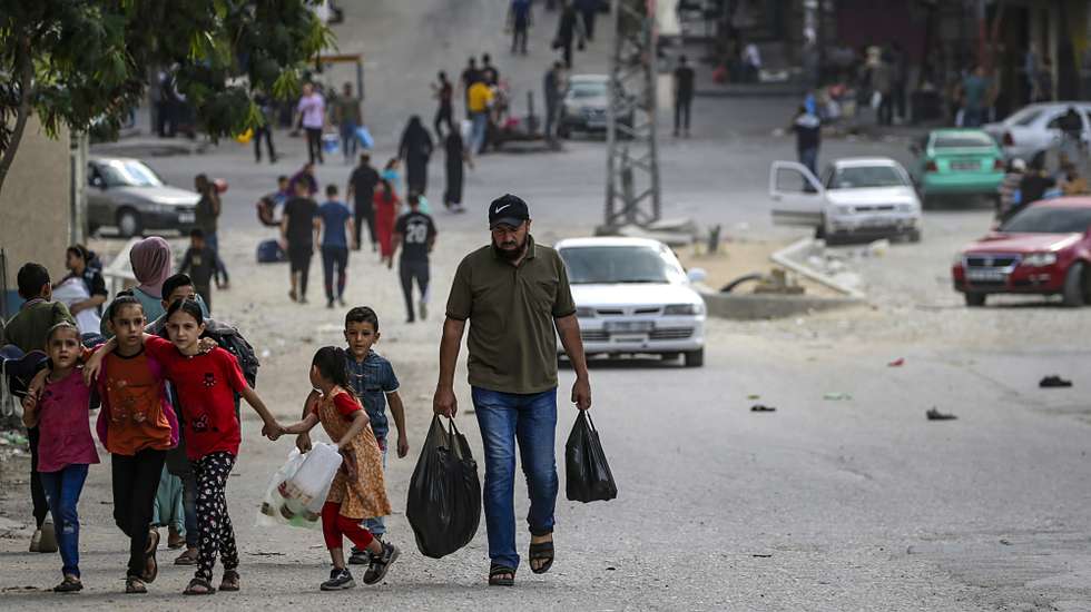 epa10922364 A Palestinian carrying food walks with his children in Al Shejaeiya neighbourhood, east of Gaza City, 16 October 2023. Israel has warned all citizens of the Gaza Strip to move to the south ahead of an expected invasion. More than 2,750 Palestinians and 1,400 Israelis have been killed according to the Israel Defense Forces (IDF) and Palestinian Health Ministry after Hamas militants launched an attack against Israel from the Gaza Strip on 07 October.  EPA/MOHAMMED SABER