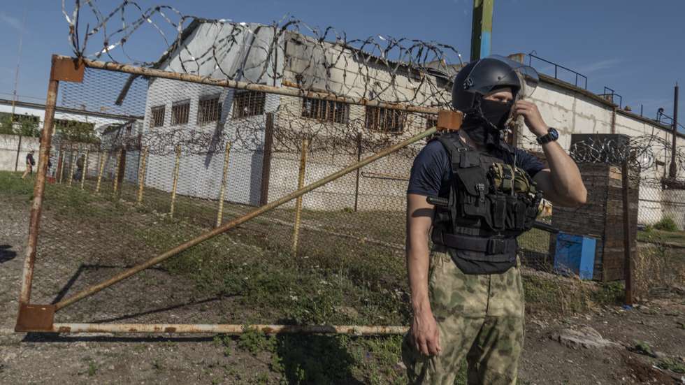 epa10115054 A picture taken during a visit to Yelenovka organised by the Russian military shows a self-proclaimed DPR militia guard outside the barrack where Ukrainian prisoners of war were held in a Yelenovka detention center in Yelenovka, Donetsk region, Ukraine, 10 August 2022. As a result of a rocket attack on a pre-trial detention center near Yelenovka on July 29, 51 Ukrainian prisoners of war were killed and 193 were wounded. ‘The investigation qualified the strike of the Armed Forces of Ukraine on the pre-trial detention center in Yelenovka as a terrorist act’, Vitalia Chernyavskaya, the official representative of the DPR Prosecutor General's Office, told reporters. The official representative of the Russian Ministry of Defense, Lieutenant-General Igor Konashenkov, reported that on July 29, the Armed Forces of Ukraine attacked a pre-trial detention center near Yelenovka from the American HIMARS multiple launch rocket system. Later, the Ministry of Defense stated that Russia, in the interests of conducting an objective investigation of the attack on the pre-trial detention center, officially invited experts from the UN and the International Committee of the Red Cross.  EPA/SERGEI ILNITSKY