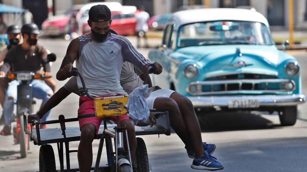 epa08987230 People wear facial masks to protect themselves from the pandemic while driving down a street in Havana, Cuba, 04 February 2021. Cuba exceeded 30,000 infections of covid-19 in eleven months of the pandemic, reporting 816 new daily cases of the disease, according to the Cuban Ministry of Public Health (Minsap).  EPA/Yander Zamora