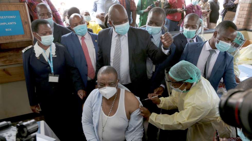 epa09021111 Vice President and Minister of Health and Child Care Constantino Chiwenga (C, sitting) receives first shot of Covid-19 vaccine, at Wilkins Hospital in Harare, Zimbabwe, 18 February 2021.  Chiwenga received the first shot of Sinopharm vaccine at the beginning of the vaccination campaign in the country that received 200,000 doses from China and is expected to vaccinate people over 60 and health workers.  EPA/AARON UFUMELI