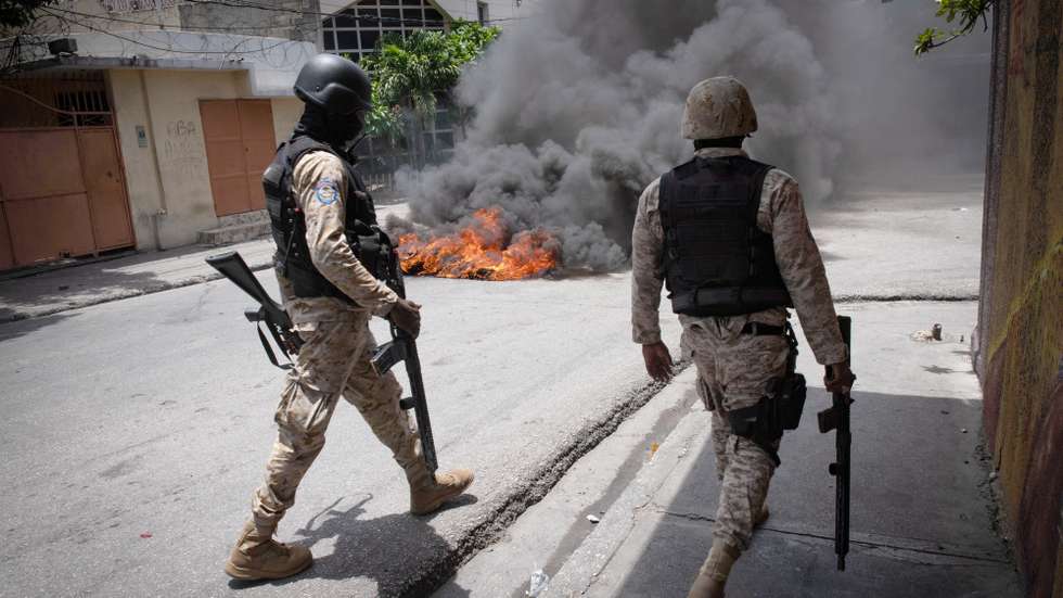 epa10800644 Policemen walk by a tire fire during a demonstration in Port-au-Prince, Haiti, 14 August 2023. Haitian National Police officers dispersed the demonstrators with tear gas after residents of the Carrefour-Feuilles area protested against the insecurity they suffer due to the action of armed gangs.  EPA/Johnson Sabin