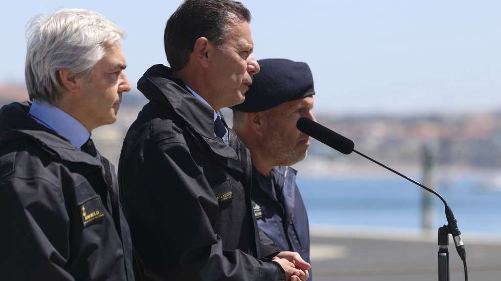 O primeiro-ministro, Luís Montenegro (C), ladeado pelo ministro da Defesa, Nuno Melo (E), discursa durante o acompanhamento das operações do navio-patrulha oceânico NRP Setúbal da Marinha Portuguesa ao largo de Cascais, 12 de agosto de 2026. TIAGO PETINGA/LUSA