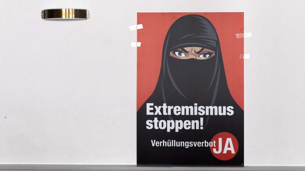epa09059579 A poster 'Stop Extremism' hangs on a wall at the meeting place of the supporters of the Burqa Ban initiative, in Bern, Switezrland, 07 March 2021. Swiss citizens vote on a proposal to prohibit the concealment of one's face in the public space. Led by right-wing groups, the so-called 'anti-burqa' initiative provides for a ban on the wearing of the niqab, as well as other non-religious forms of face concealment.  EPA/PETER KLAUNZER