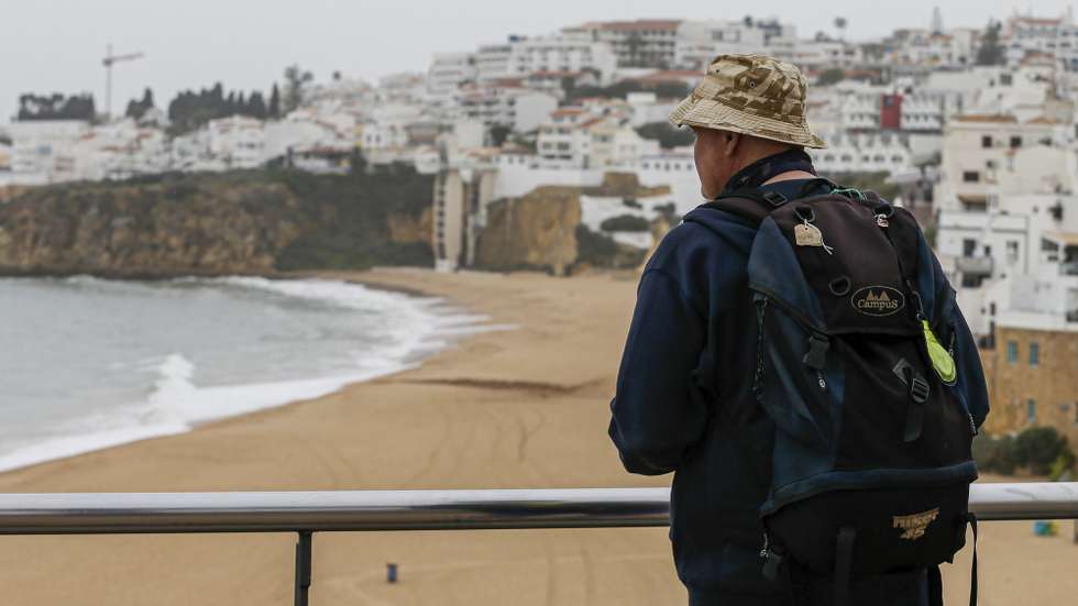 Um turista observa a praia de Albufeira completamente vazia depois do Presidente da República, Marcelo Rebelo de Sousa, ter declarado ontem o estado de emergência devido á pandemia de Covid-19, Albufeira, 19 de março de 2020. A Direção-Geral da Saúde (DGS) elevou hoje o número de casos confirmados de infeção para 785, mais 143 do que na quarta-feira. O número de mortos no país subiu para três. LUÍS FORRA/LUSA