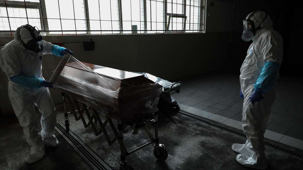 epa08347892 Employees of a funeral home fully protected with an integral mask and wearing protective suits against radioactive contamination and biological agents, covering with plastic wrap the coffin containing a body of a man over 80 years old who died in his home as a victim of covid-19, in Lisbon, Portugal, 03 April 2020 (Issued 07 April 2020). Portugal is in state of emergency until 17 April 2020. Countries around the world are taking increased measures to stem the widespread of the SARS-CoV-2 coronavirus which causes the Covid-19 disease.  EPA/MIGUEL A. LOPES  ATTENTION: This Image is part of a PHOTO SET