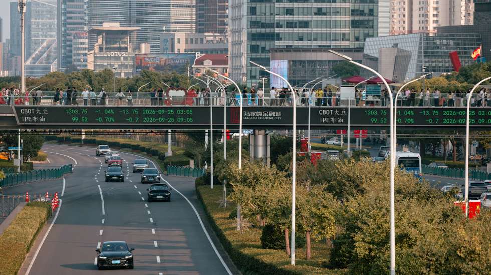 epa13262481 People walk across a pedestrian bridge with screen showing the latest stock exchange and economy data, in Shanghai, China, 25 September 2026.  EPA/ALEX PLAVEVSKI