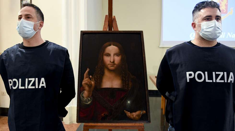 epa08948081 Two police officers stand next to the recovered painting 'Salvator Mundi', in Naples, southern Italy, 18 January 2021 (issued 19 January 2021). The 15th-century painting of Christ the Saviour from the school of Leonardo da Vinci, part of the 'DOMA' collection, has been recovered by police during a search in Naples after it was stolen from the Basilica di San Domenico Maggiore in the southern Italian city two years ago. A 36-year-old, the owner of the flat, has been detain on suspicion of receiving stolen goods, media reported.  EPA/CIRO FUSCO