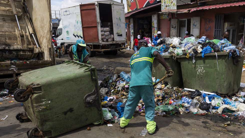 Um funcionário limpa a estrada junto a latões do lixo derrubados, em Luanda, Angola, 17 de abril de 2026.  JOSÉ SENA GOULÃO/LUSA