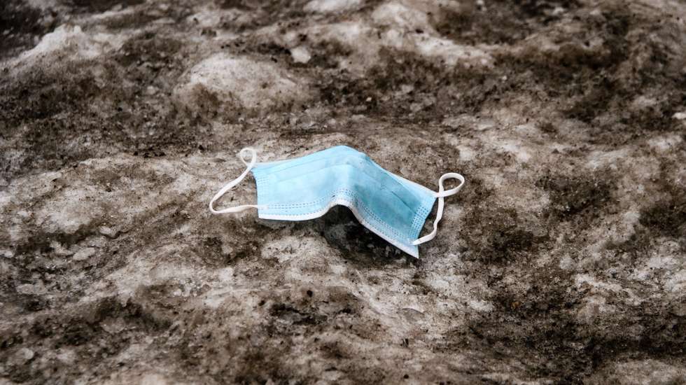 epa09014742 A used surgical face mask lies on dirty snow in Berlin, Germany, 15 February 2021.  EPA/CLEMENS BILAN