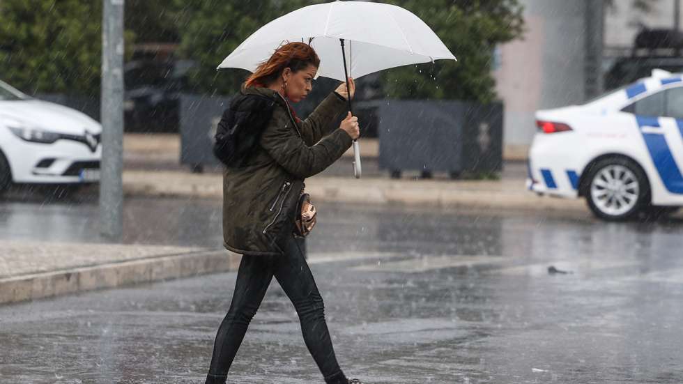 Uma traseunte passa com chapéu de chuva na zona de Algés em Oeiras num dia de temporal, 14 de dezembro de 2022. TIAGO PETINGA/LUSA