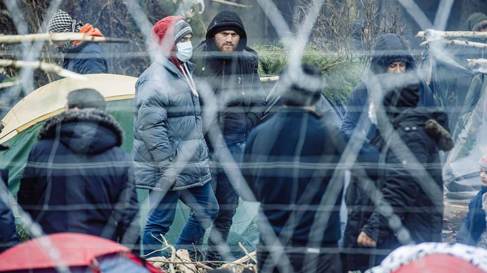 epa09581991 A handout photo made available by Territorial Defense Forces shows migrants behind the border fence in Belarus near the Polish-Belarusian border crossing in Kuznica, eastern Poland, 11 November 2021 (issued 14 November 2021). Poland has been struggling to stem the flow of Middle Eastern and African asylum-seekers, refugees and migrants crossing into Poland from Belarus. The Polish government says the migrants have been invited to Belarus by Alexander Lukashenko, the country's president, allegedly under the promise they will be able to live in the EU.  EPA/IREK DOROZANSKI HANDOUT POLAND OUT HANDOUT EDITORIAL USE ONLY/NO SALES