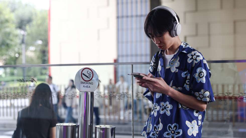 epa12391835 A man uses his cellphone on a street in the Central Business District (CBD) area in Beijing, China, 20 September 2025.  EPA/WU HAO