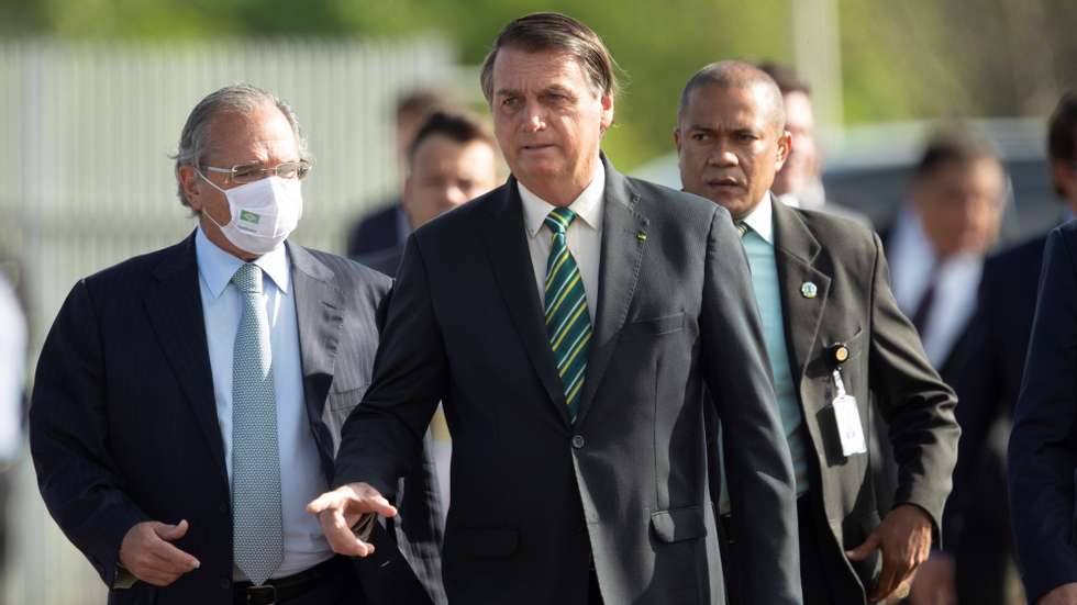 epa08777585 Brazilian President Jair Bolsonaro (C), walks with Economy Minister Paulo Guedes (L) towards the raising of the National Flag before the 38th Meeting of the Governing Council, at the Palace of the Alvorada, in Brasilia, Brazil, 27 October 2020.  EPA/Joedson Alves