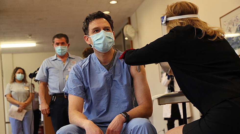 epa08884295 Dr. Christian Arbelaez (L) is administered the first coronavirus COVID-19 vaccine injection in the state at Rhode Island Hospital in Providence, Rhode Island, USA, 14 December 2020. High-risk health care employees including housekeeping, nursing, respiratory therapy, intensive care, and emergency medicine got the first doses of the coronavirus COVID-19 vaccine in the state.  EPA/SUZANNE KREITER / THE BOSTON GLOBE EDITORIAL USE ONLY, NO SALES