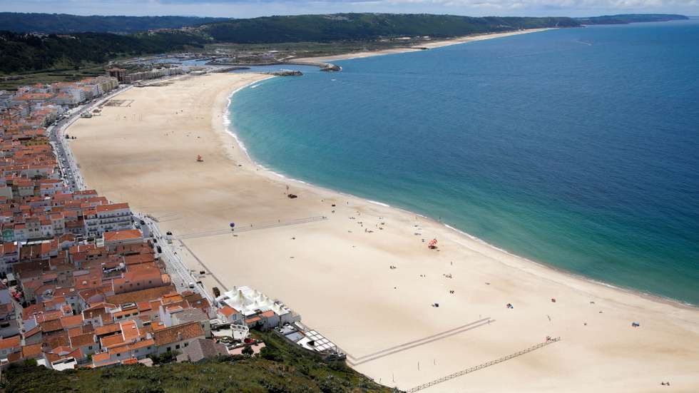 Sem sol e com poucos banhistas, a época balnear arrancou hoje com mais gente na marginal e nas esplanadas do que na praia da Nazaré, onde não falta espaço para cumprir distâncias de segurança, Nazaré, Leiria, 6 de junho de 2020. Com algumas nuvens a toldar o sol e a tornar a praia menos convidativa, era na marginal da Nazaré que manhã cedo se concentrava o movimento, com passeantes e atletas a cruzarem-se no passeio largo. PAULO CUNHA /LUSA