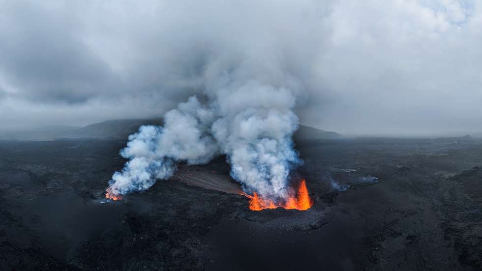 epa12248363 Smoke and lava rise from a volcano eruption near Reykjanes, Iceland, 19 July 2025. According to the Icelandic Meteorological Office, a magma flow began at the Sundhnuk crater range on 16 July.  EPA/JAKOB VEGERFORS