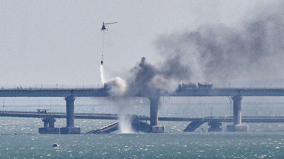 epaselect epa10230640 A firefighter helicopter pours water on fire on a collapsed part of the Kerch Strait bridge in Crimea, 08 October 2022. According to Russian authorities, "an explosion was set off at a cargo vehicle on the motorway part of the Crimean bridge on the side of the Taman peninsula, which set fire to seven fuel tanks of a train that was en route to the Crimean peninsula. Two motorway sections of the bridge partially collapsed."  EPA/STRINGER