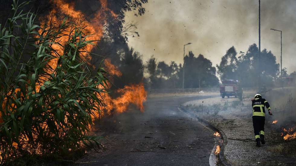 Um bombeiro protege-se do fogo durante o incêndio florestal em Andrinos, às portas da cidade de Leiria, 13 de julho de 2022. Dezasseis dos 18 distritos de Portugal continental estão hoje sob aviso vermelho, o mais grave, devido ao tempo quente, com mais de uma centena de concelhos em perigo máximo de incêndio rural. NUNO ANDRÉ FERREIRA/LUSA