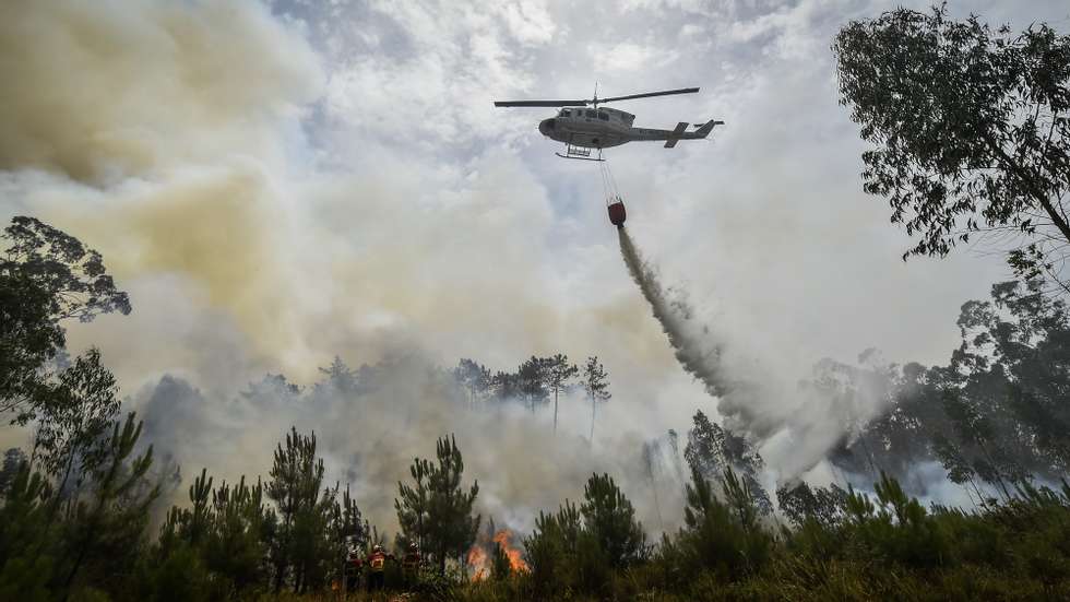 Um helicóptero de combate aos incêndios faz uma descarga de água sobre o fogo durante o incêndio florestal na aldeia do Lavradio, Ourém, 13 de julho de 2022. Dezasseis dos 18 distritos de Portugal continental estão hoje sob aviso vermelho, o mais grave, devido ao tempo quente, com mais de uma centena de concelhos em perigo máximo de incêndio rural. NUNO ANDRÉ FERREIRA/LUSA