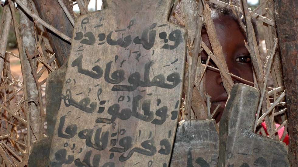 epa00808818 A pupil at a Koranic school or Madrassa looks through the fence where wooden boards with versus from the Koran lie against the inside of the makeshift school wall Saturday, 2 September, 2006.  Somali's Transional Federal Government, which controls only a small area of the coluntry around Baidoa, has opened talks on power sharing with the Islamic Court Union, who control most of the rest of the country, in Khartoum Sudan but oservers warn that if the talks failed this horn of Africa nation would fall into a new round of civil strife.  EPA/GEORGE MULALA