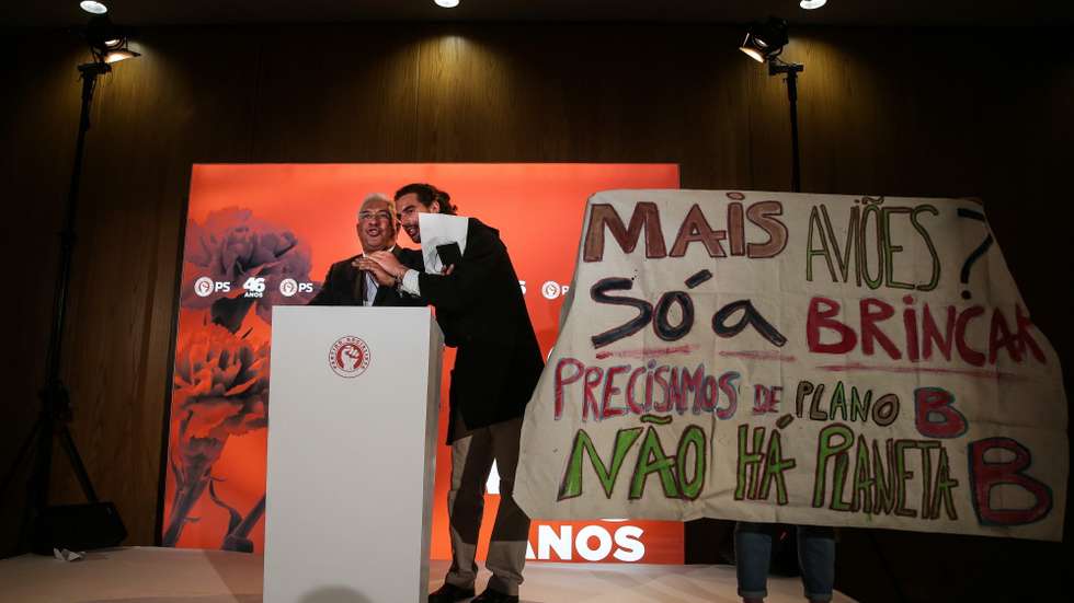 Os ativistas aproximaram-se do palco e lançaram aviões de papel, mostrando um cartaz onde se lia "Mais aviões só a brincar"