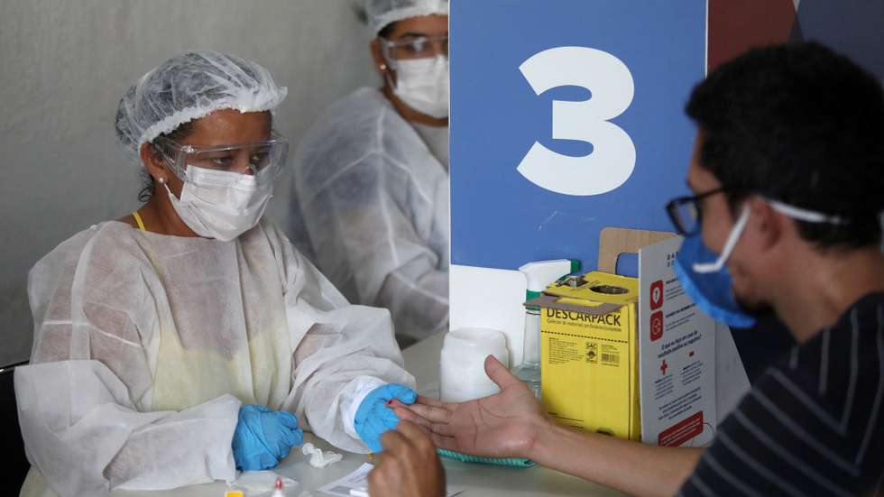 epa08747818 A man takes a test for coronavirus in the Mare favela , in Rio de Janeiro, Brazil, 13 October 2020 (issued 15 October). The streets returned to their dynamics in Mare. In the midst of crowded commerce and traffic congestion, this complex of favelas in Rio de Janeiro is experiencing a "new normal" in the midst of a pandemic. Poverty and violence remain, but solidarity is now more visible.  EPA/FABIO MOTTA