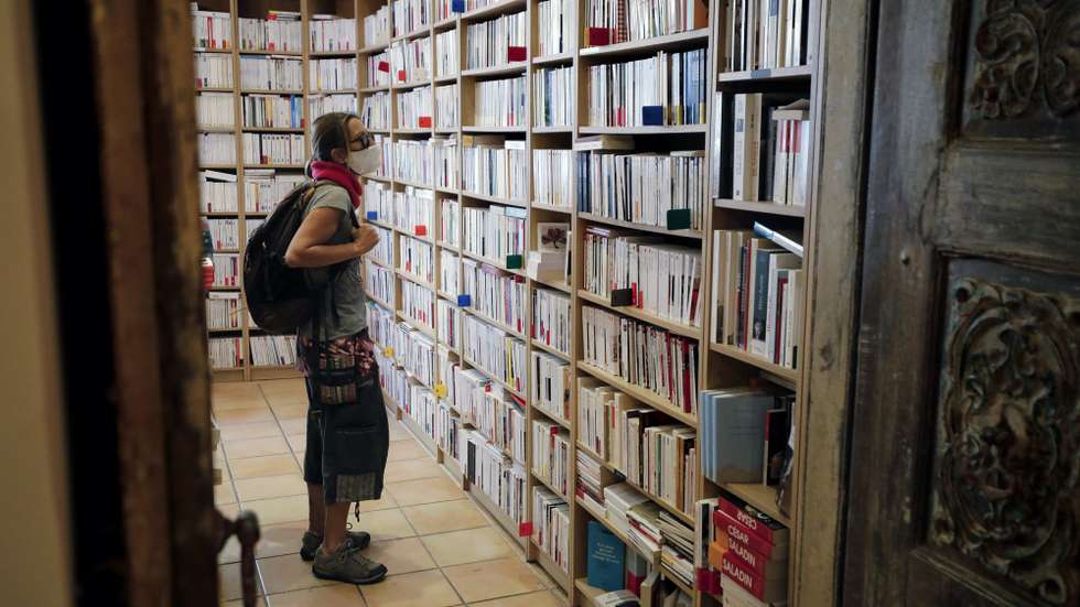 epa08823805 A woman looks at books inside the book store 'Autant du Livre' in Cannes, France, 16 November 2020. Owner Florence Kammermann keeps her book store open during the second lockdown following the announcement of French President Macron who announced the closure of non-essential stores including book stores.  EPA/SEBASTIEN NOGIER