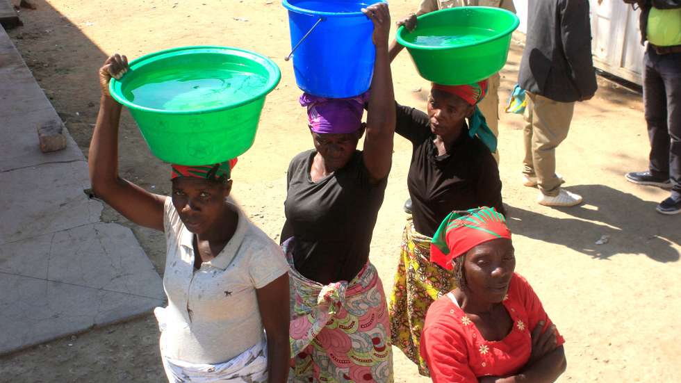 Mulheres transportam na cabeça alguidares com água, no Huambo, Angola, 30 de maio de 2019. AMPE ROGÉRIO/LUSA