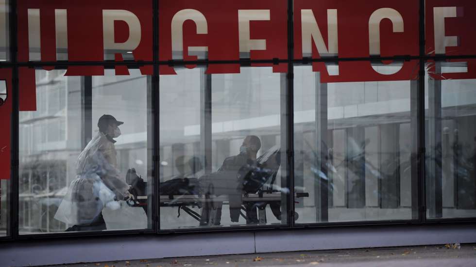 epa08780297 Medical staff wearing protective facial masks transport a patient on a gurney inside the Tenon Hospital in Paris, France, 28 October 2020. French President Emmanuel Macron will unveil new measures to stem the Covid-19 epidemic in a television speech on 28 October 2020.  EPA/JULIEN DE ROSA