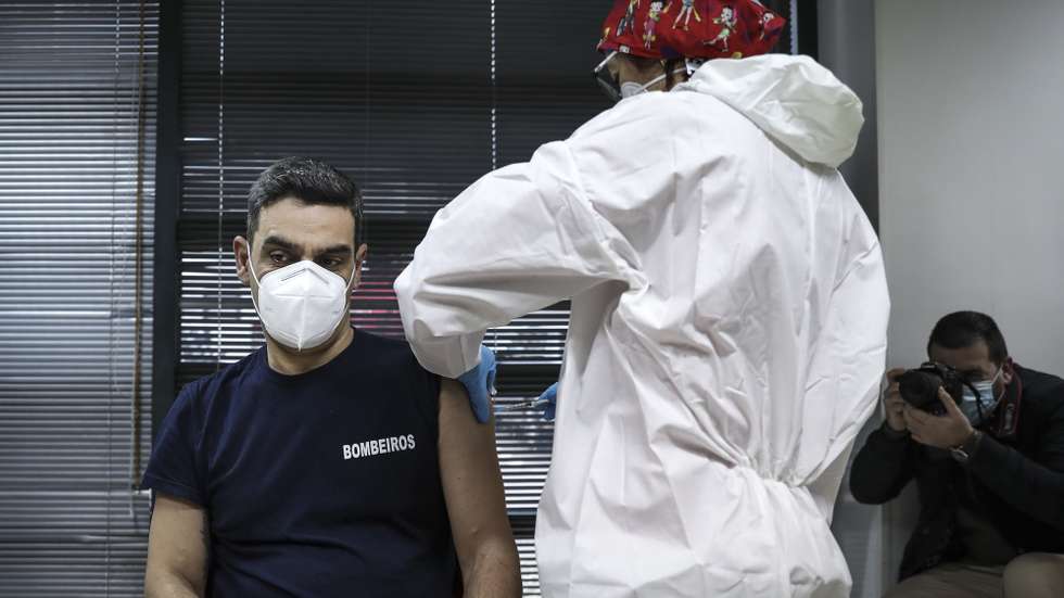 Um bombeiro é vacinado por uma profissional de saúde