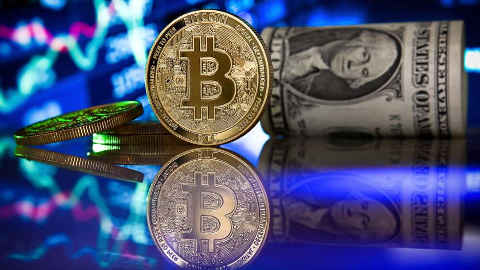 epa09017765 (FILE) - A bitcoin in front of a monitor showing a stock barometer in Duesseldorf, Germany, 20 January 2021 (reissued 17 February 2021). Cryptocurrency Bitcoin's value value crossed the 50,000 USD treshold for the first time on 16 February 2021. The value of Bitcoin has risen 74 per cent in 2021 following Tesla saying it plans to accept Bitcoin as payment for its cars in future, and  institutional investors showing interest in the currency.  EPA/SASCHA STEINBACH