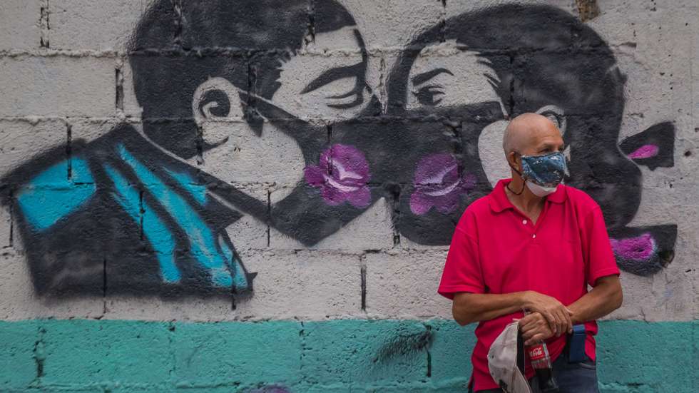 epa09109409 A man stands next to a mural alluding to the use of a mask to protect of covid-19, in Caracas, Venezuela, 31 March 2021. When vaccines have allowed the world to take a breath, Venezuela holds its breath. After a year of living with covid-19, the Brazilian mutation has caused the great wave of infections to reach the Caribbean country, with citizens scared by the crisis itself and the possibility of hospital collapse.  EPA/Miguel Gutierrez
