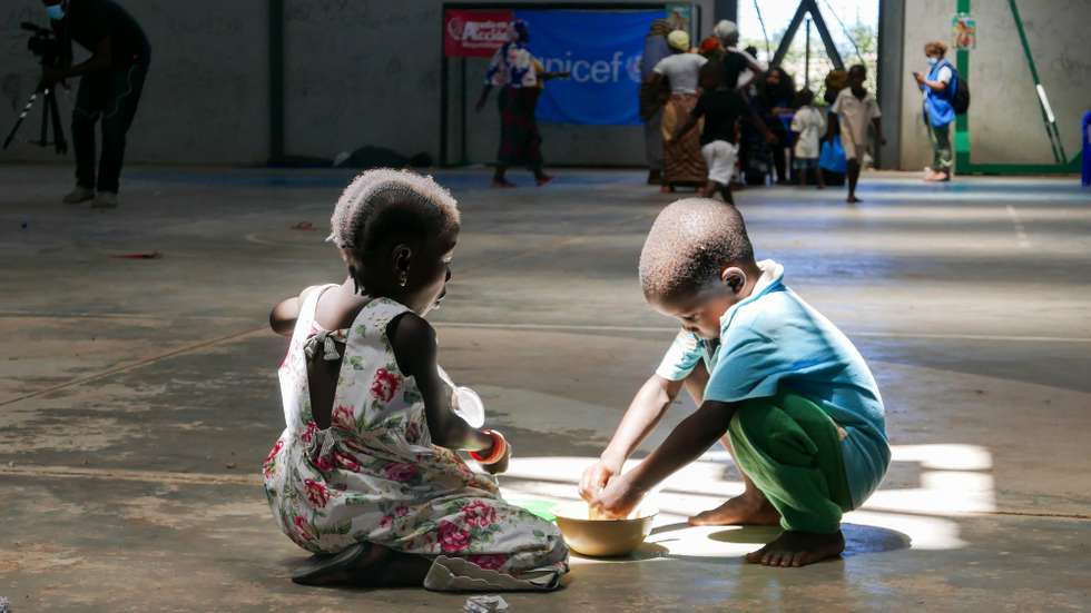 Duas crianças no pavilhão desportivo, no bairro Expansão, em Pemba, alimentam-se com refeições confecionadas por um grupo de mulheres de Pemba, que decidiu fazer hoje para os deslocados do ataque a Palma, em vez de descansar no feriado do Dia da Mulher Moçambicana, Cabo Delgado, Moçambique, 07 de abril de 2021. Os ataques são só uma ponta do problema que se estende desde as zonas de conflito até Pemba e outras cidades, seguras, mas agora sobrelotadas com a vaga de 700.000 deslocados em três anos e meio de conflito. (ACOMPANHA TEXTO). LUÍS MIGUEL FONSECA/LUSA