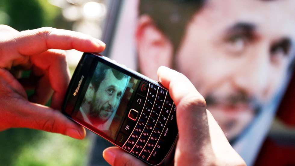 epa02377329 A Lebanese man taking a picture of a portrait of Iranian President Mahmud Ahmadinejad in the southern Lebanese town of Maroun al-Ras 06 October 2010. The Iranian is scheduled to pay a visit to Lebanon on October
13-14.  EPA/HASSAN BAHSOUN