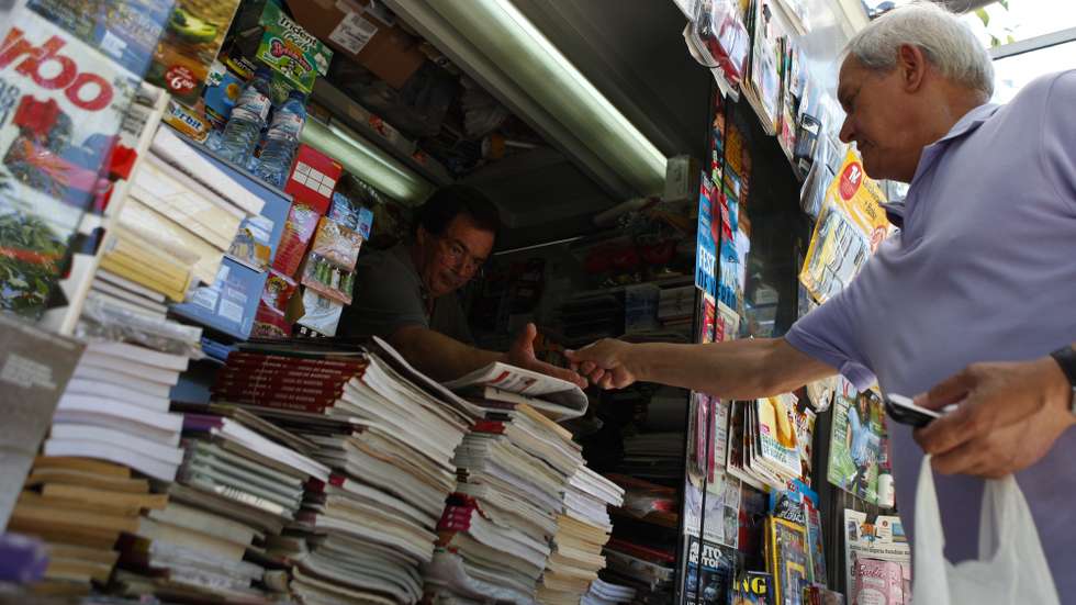 Um popular compra os jornais num quiosque de venda de revistas e jornais, em Lisboa, 13 de julho de 2013. Nos últimos anos, na Avenida da Liberdade, em miradouros pelas sete colinas, nos jardins, à beira Tejo, nas praças, os quiosques foram nascendo ou ganhando vida “como cogumelos” e, reinventando um centenário hábito lisboeta, puseram a cidade a mexer. (ACOMPANHA TEXTO). MIGUEL A. LOPES / LUSA