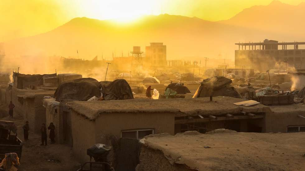 epa08890718 An Afghan woman who was displaced from volatile areas works on the top of her house roof in temporary shelters, on the eve of International Migrants Day in Kabul, Afghanistan, 17 December 2020. International Migrants Day is observed annually on 18 December to raise awareness of the efforts, contributions and challenges made and faced by migrants and internally displaced persons (IDPs).  EPA/HEDAYATULLAH AMID