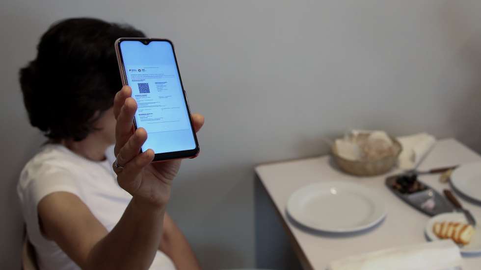 Cliente exibe o certificado digital no interior de um restaurante em Lisboa, após o Governo decreta que os restaurantes em concelhos de risco elevado ou muito elevado – um total de 60 – passam a ter de exigir certificado digital ou teste negativo à covid-19 a partir das 19:00 de sexta-feira e aos fins de semana para refeições no interior, Lisboa, 10 de julho de 2021. As pessoas em esplanadas que precisarem de entrar nos restaurantes para acesso aos serviços comuns, como instalações sanitárias, ou para efetuarem pagamento, estão dispensadas de apresentar um teste negativo à covid-19 ou o certificado digital. MANUEL DE ALMEIDA/LUSA